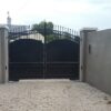 Tall decorated black steel gate with arched solid panels