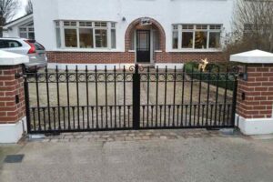 Black steel gate set between two short redbrick pillars.